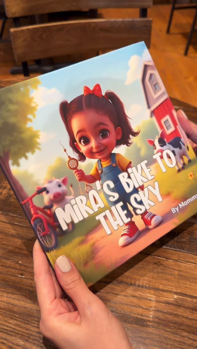 Children's personalized storybook titled Mira's Bike to the Sky held by two hands.