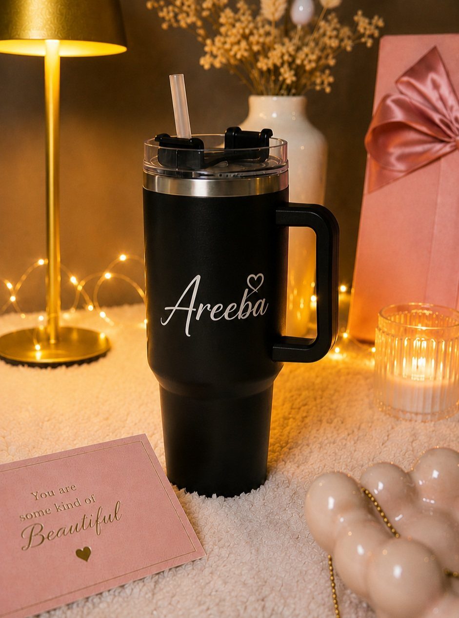 Black personalized tumbler with the name Areeba on a cozy, lit background.