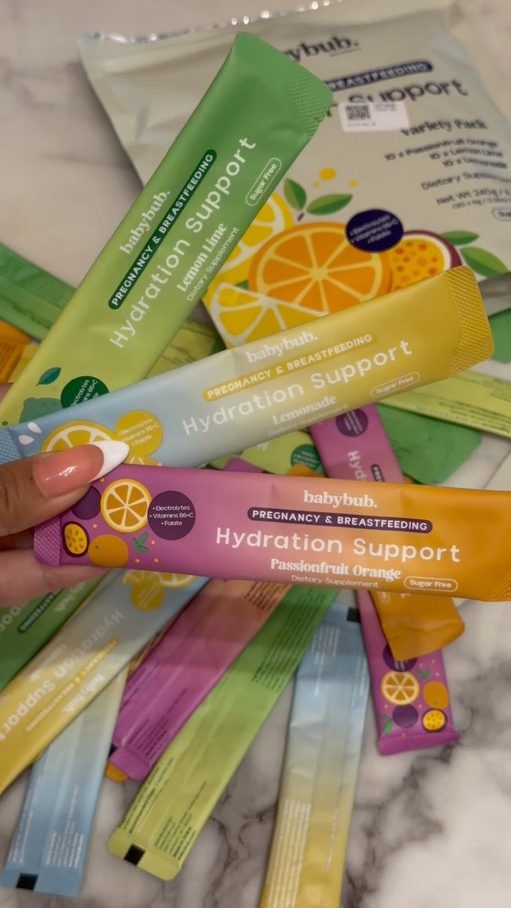 Pregnancy hydration support sachets in various colors held over a marble background.