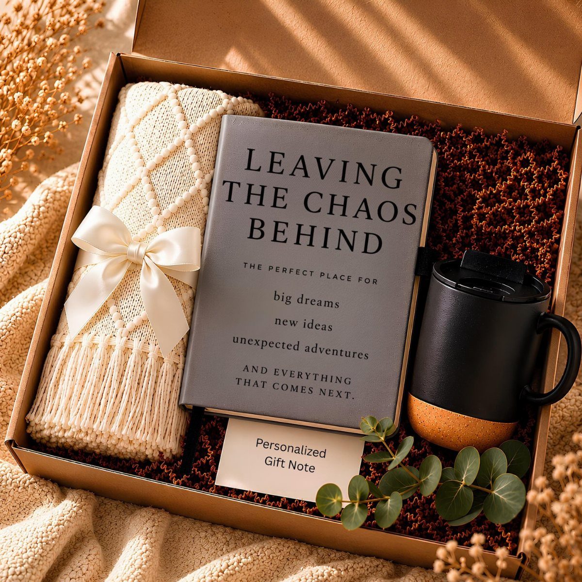 Gift box with a retirement journal, knitted throw, travel mug, and eucalyptus leaves.