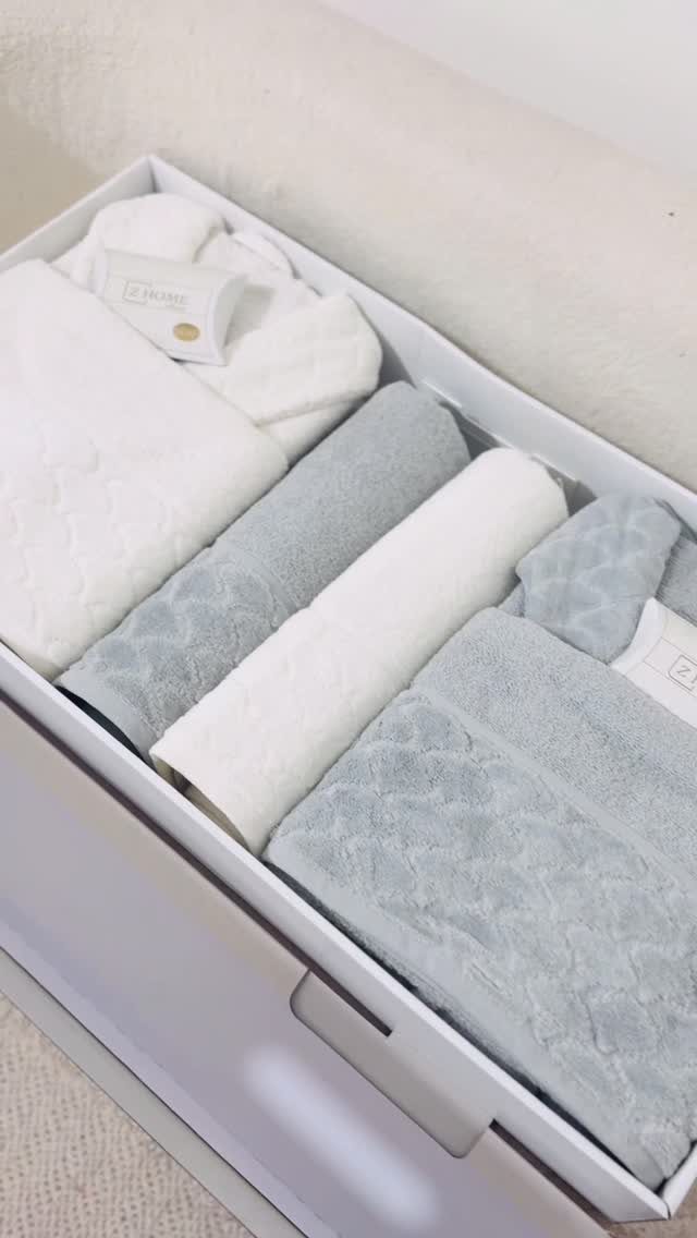 White and light blue towels neatly arranged inside a white gift box.