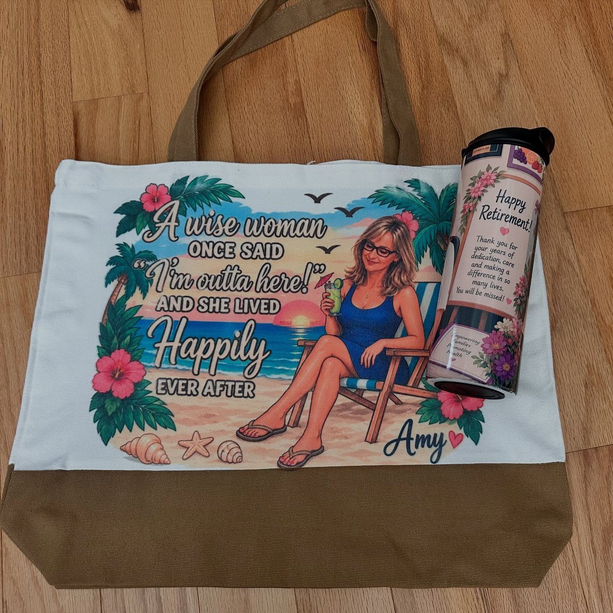 Personalized retirement tote bag with beach illustration and matching tumbler on wooden floor