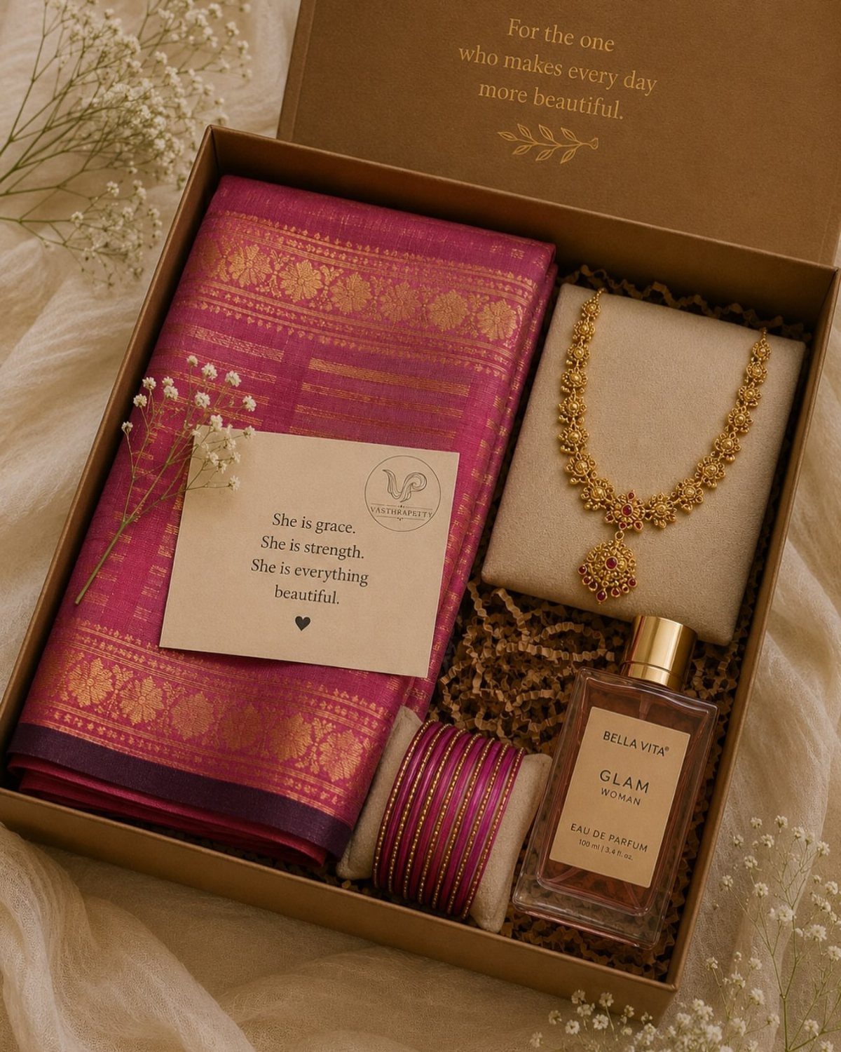 Gift box with pink silk saree, gold necklace, perfume, and bangles for women.