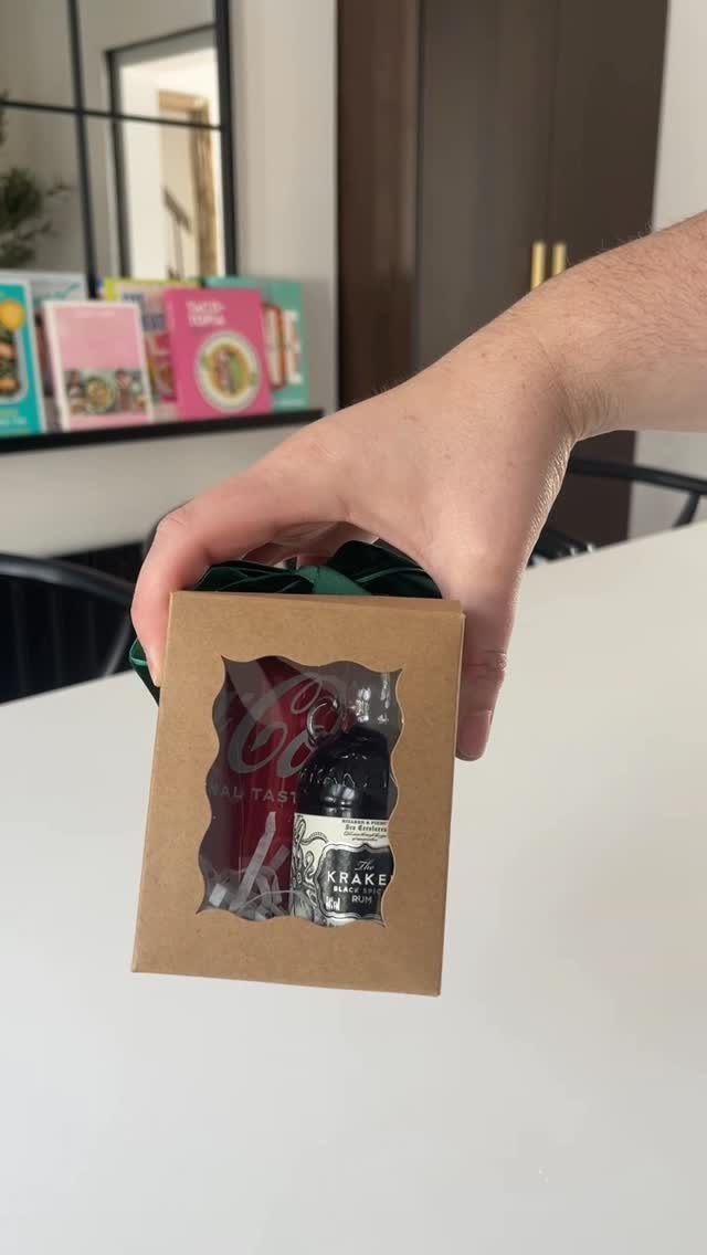 Hand holding a small brown gift box containing miniature alcohol bottles and cans