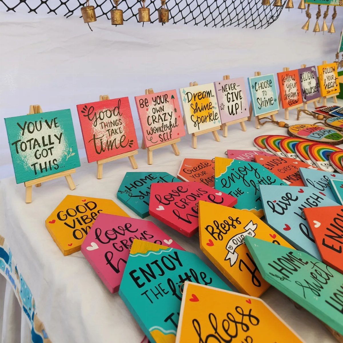 Colorful hand-painted wooden canvases with motivational quotes displayed on small easels.