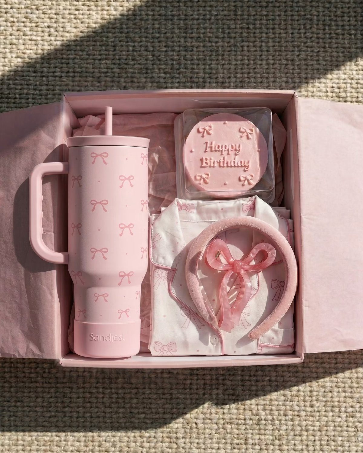 Pink gift box with a bow-patterned tumbler, birthday treat, and matching accessories.