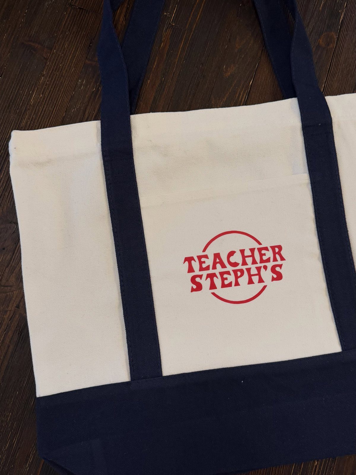 White canvas tote bag with navy straps and red Teacher Steph's text print.
