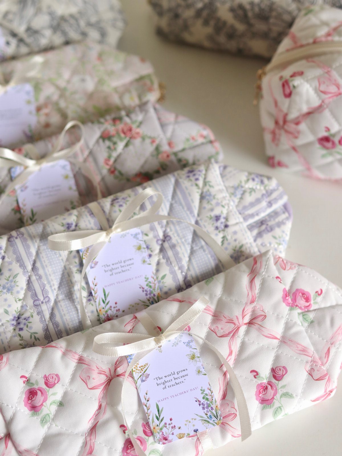 Floral quilted fabric pouches tied with white ribbons and gift tags.