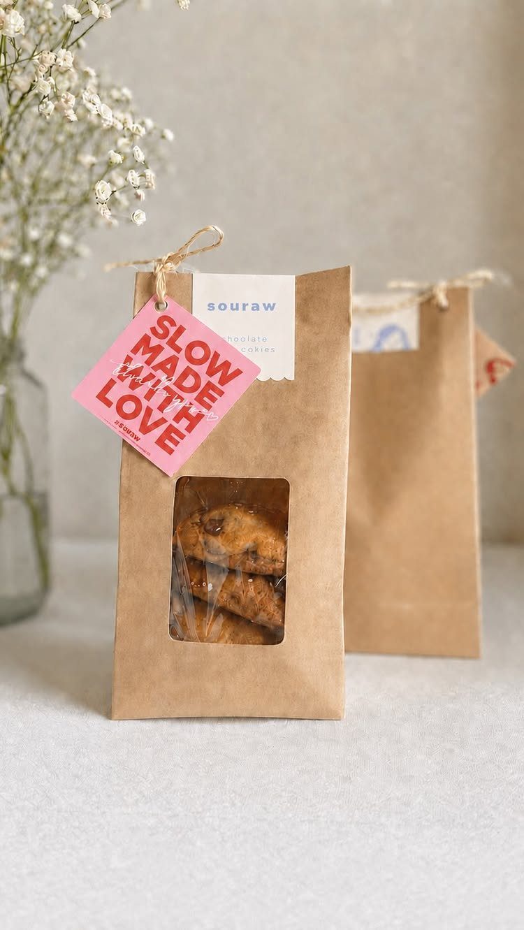 Brown paper bags containing cookies with a pink 'Slow Made With Love' tag.