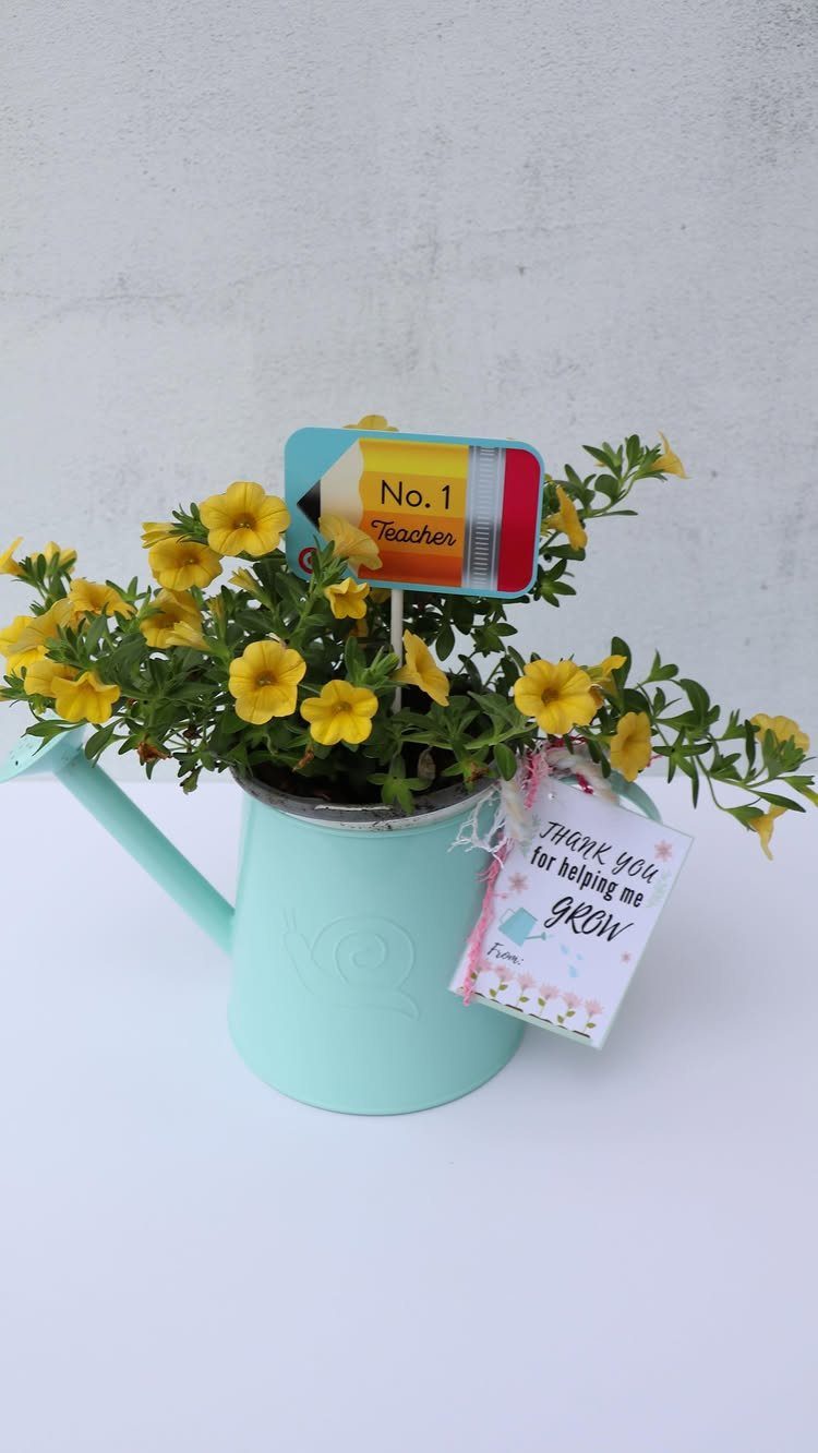 Yellow flowers in a blue watering can with a teacher appreciation gift tag.