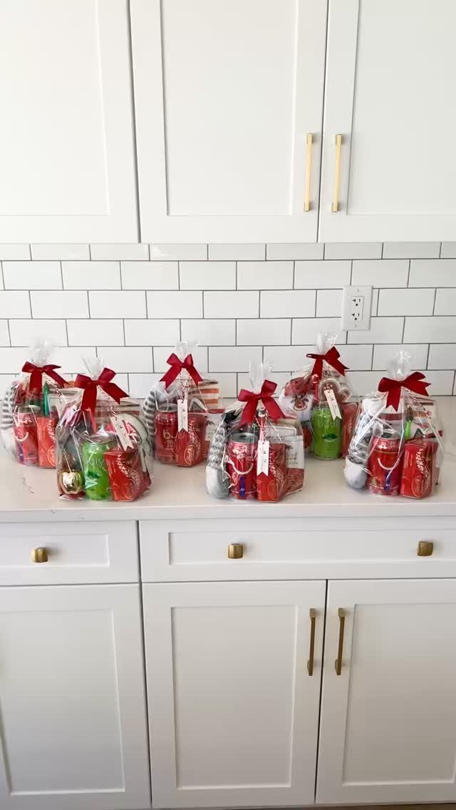 Six clear gift bags with red ribbons filled with red and green treats.