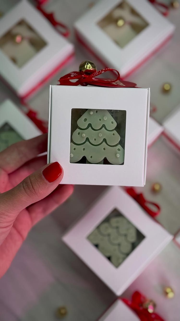 Green Christmas tree cookies in small white gift boxes with red ribbons.