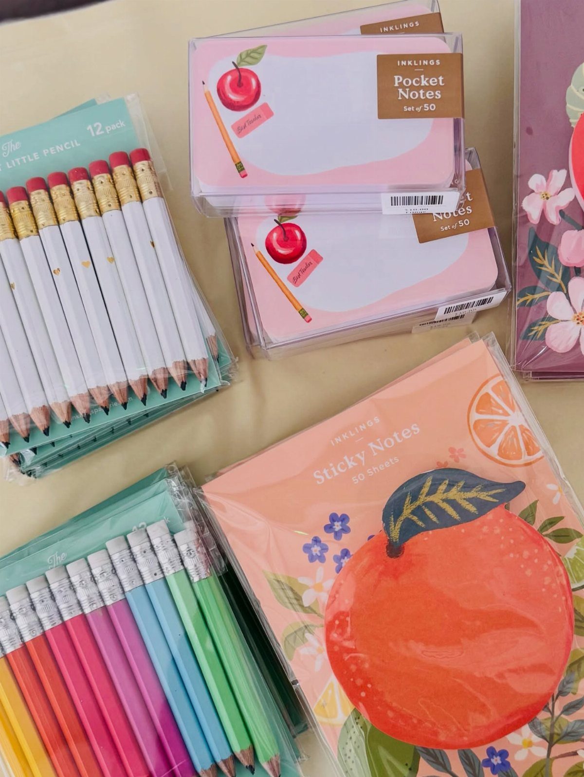 Stationery set with colorful pencils, apple-themed pocket notes, and orange sticky notes.