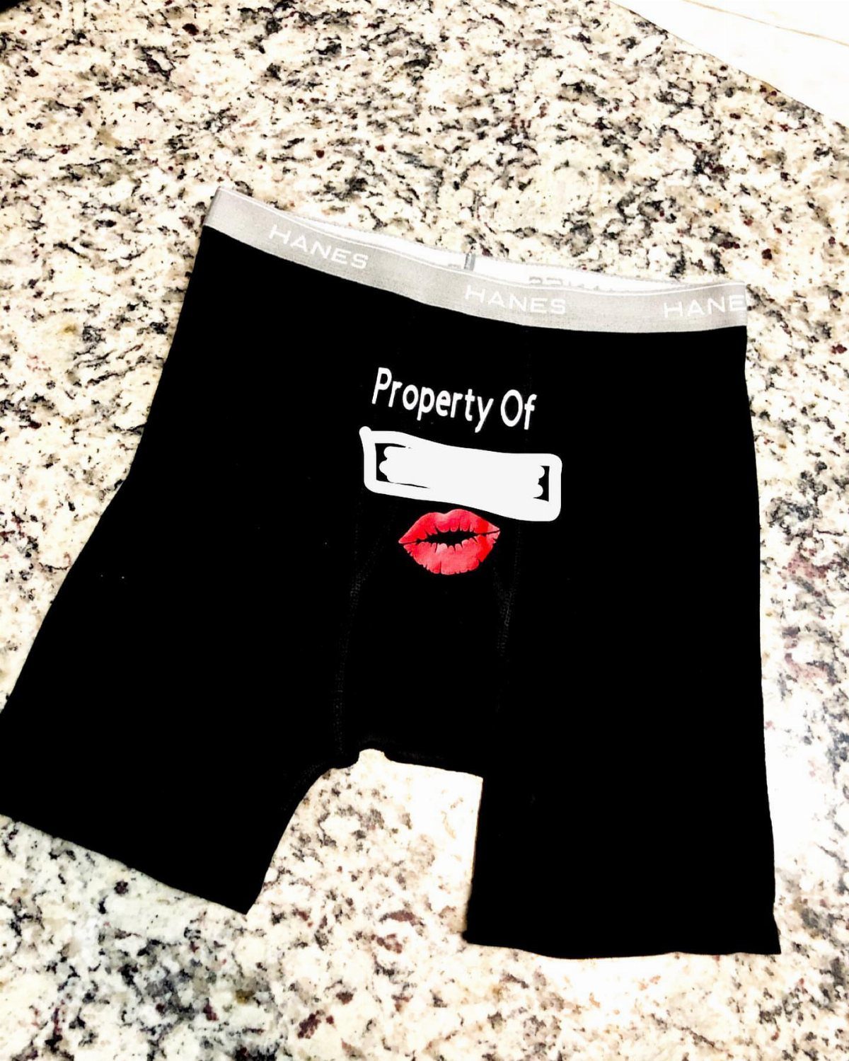 Black boxer briefs with Property Of text and a red kiss mark.