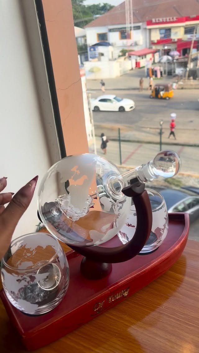 Glass globe decanter and glasses on a red tray by a window