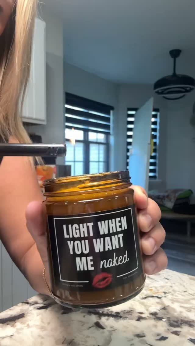 Brown wax candle in a glass jar with a suggestive black label.
