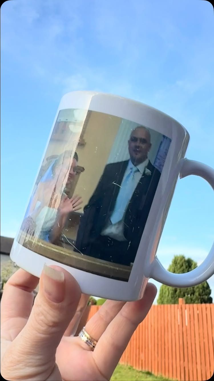 White ceramic mug with a wedding photo held against a blue sky background