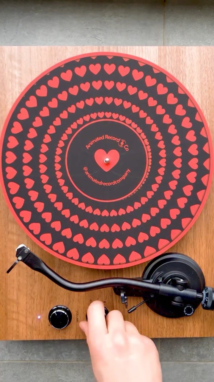 Vinyl record with red heart patterns spinning on a wooden record player