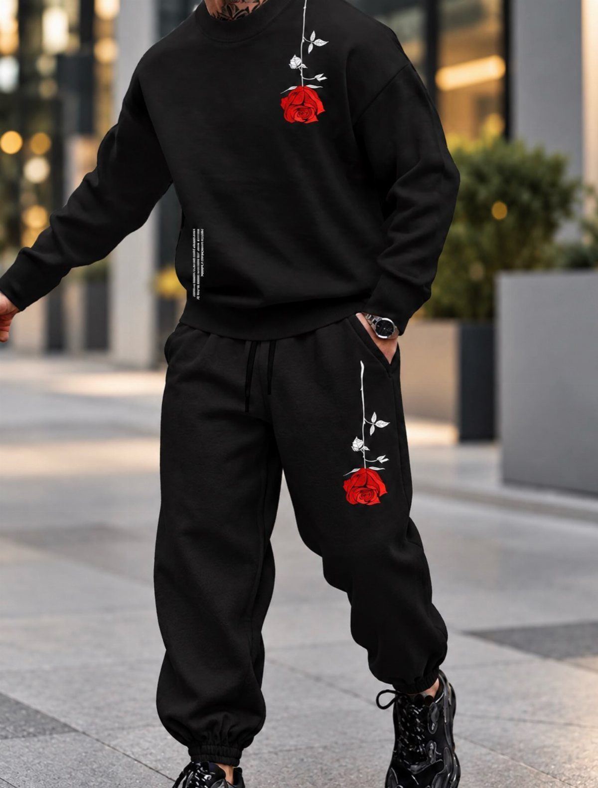 Person wearing black sweatshirt and joggers with red rose graphics on a city street