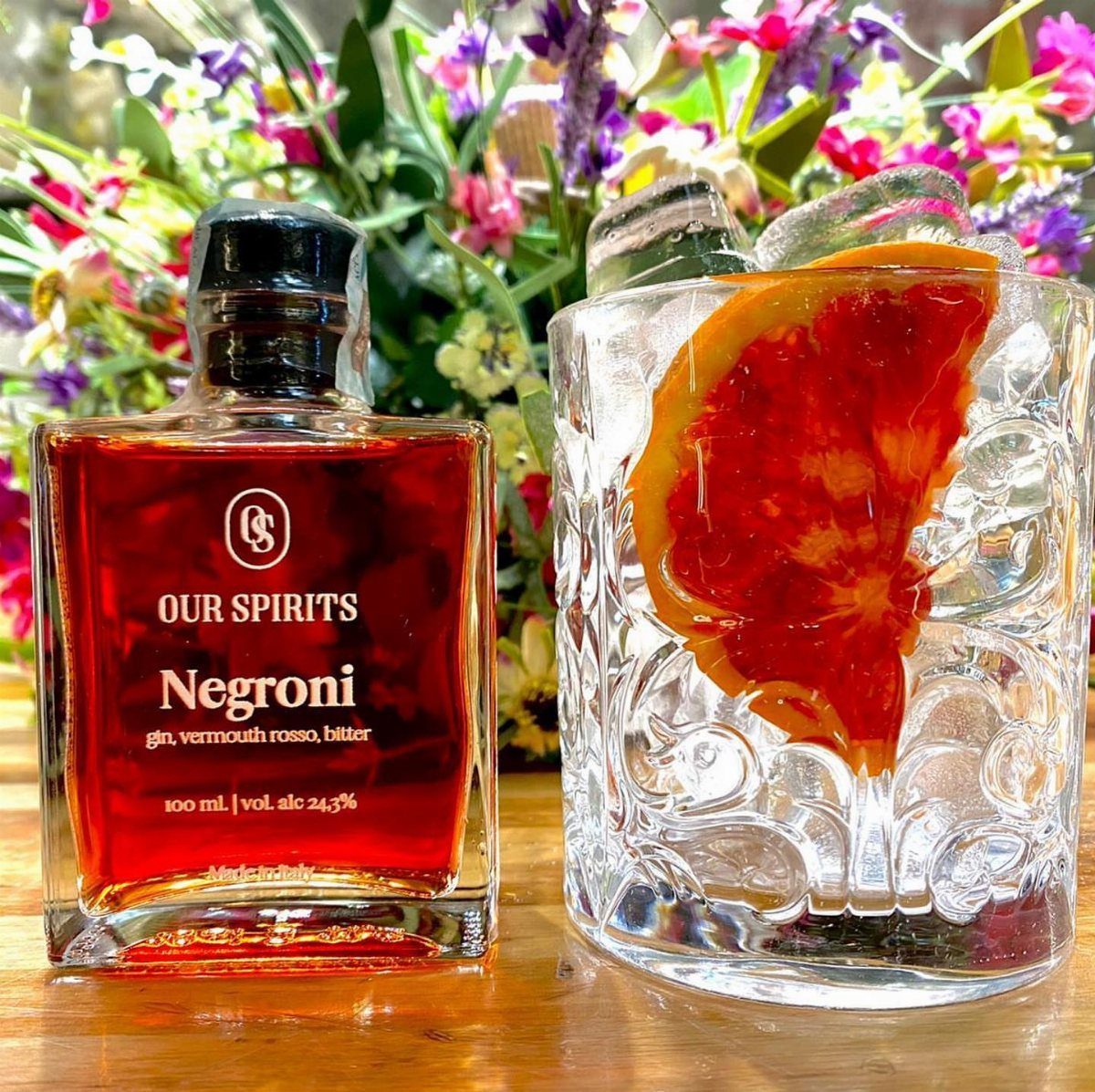 Negroni cocktail bottle and a crystal glass with blood orange and ice.