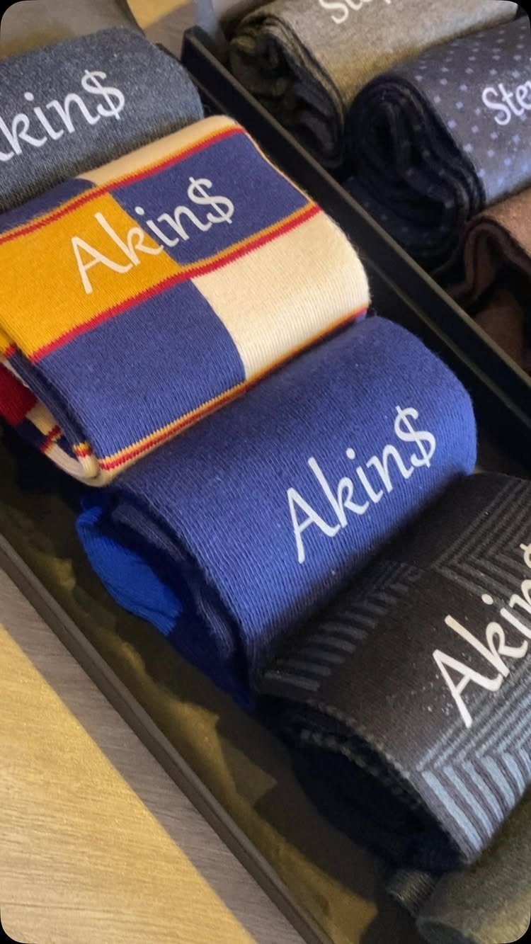 Folded colorful socks with the name Akin$ embroidered in white on the cuffs.