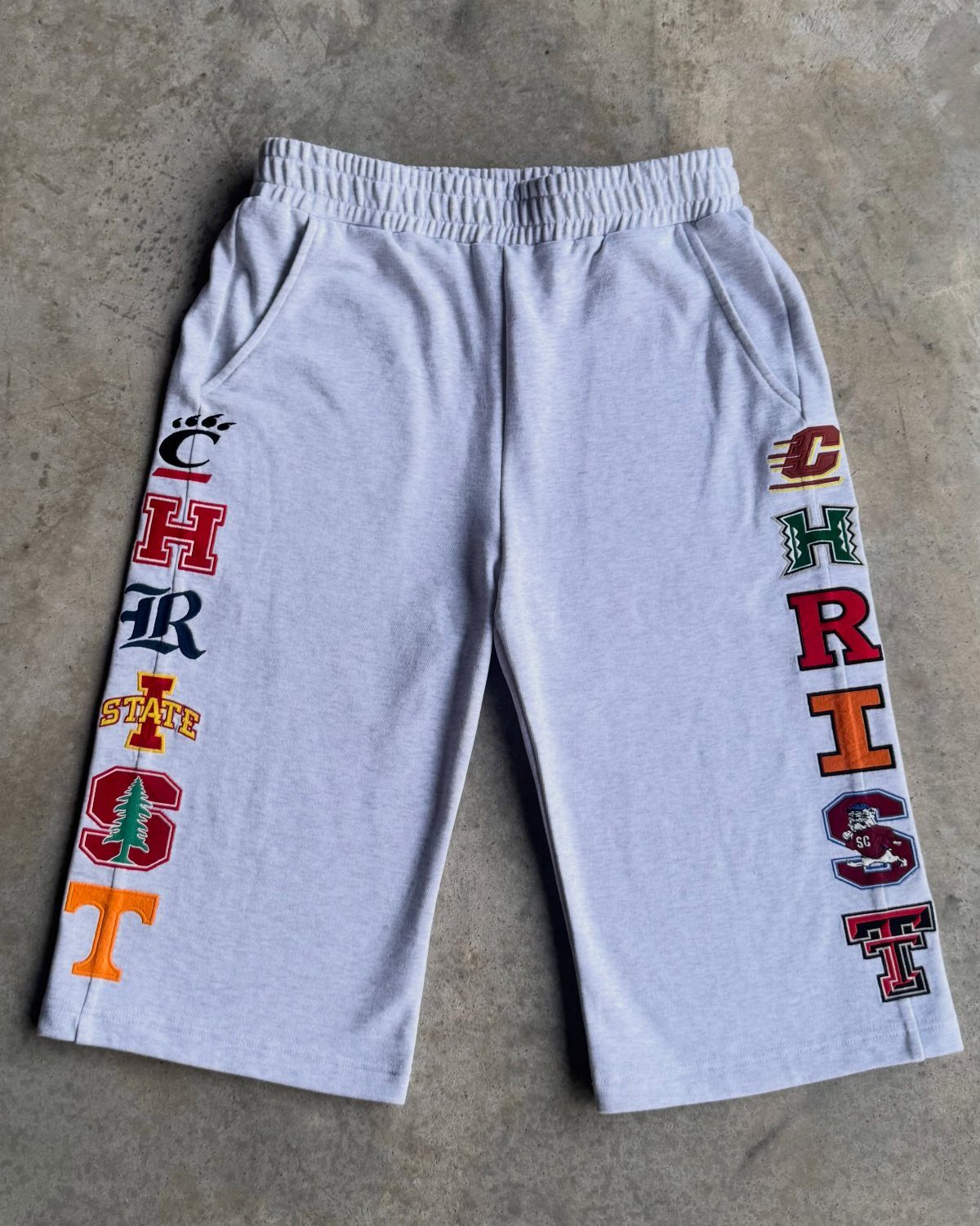 Grey cropped sweatpants with colorful collegiate letters spelling CHRIST on both legs.