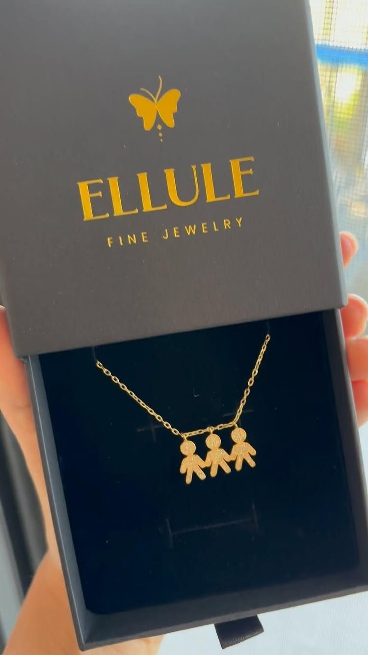 Gold necklace with three child-shaped charms inside a black Ellule jewelry box.