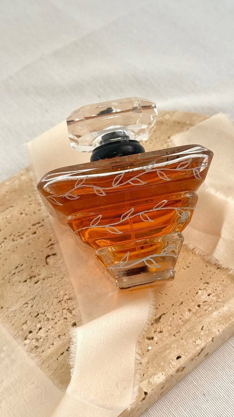 Amber glass perfume bottle with leaf patterns on a travertine stone slab