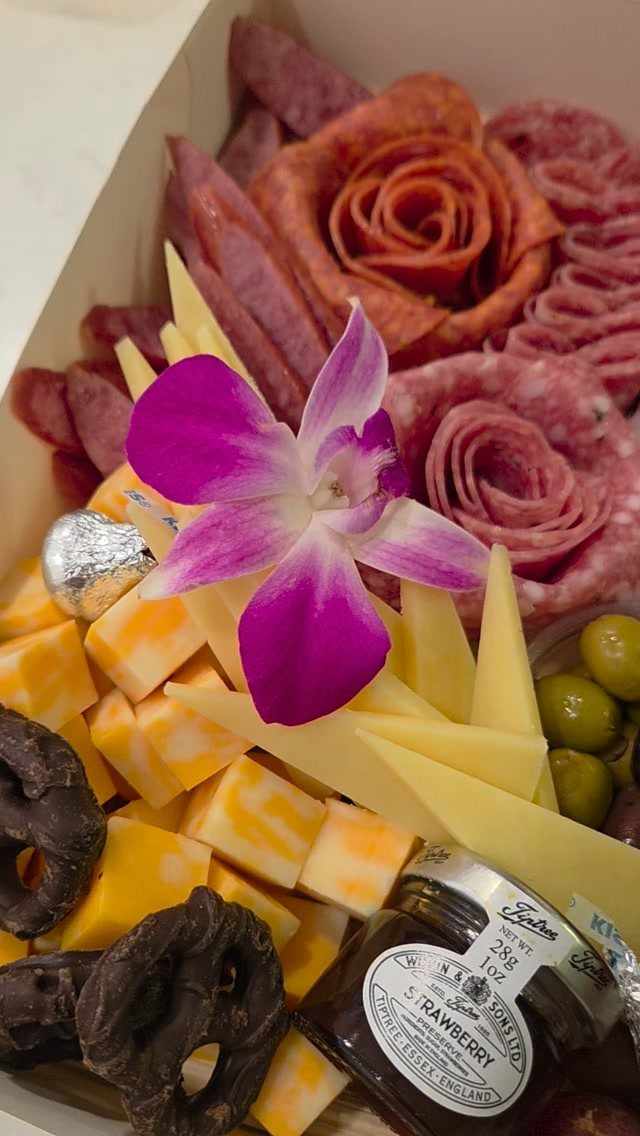 Gourmet charcuterie gift box with salami roses, cheese, olives, and a purple orchid.