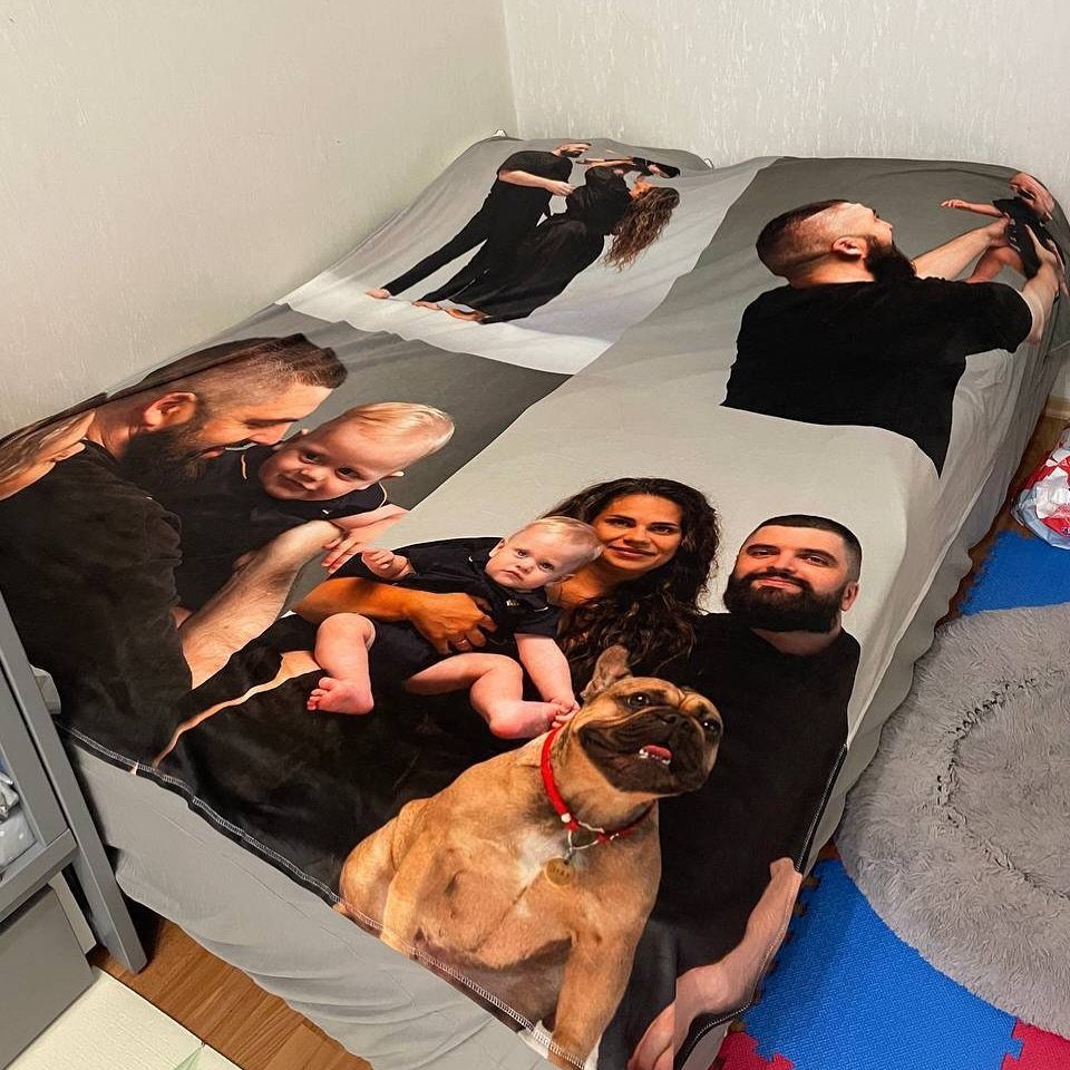 Custom photo blanket on a bed featuring a family and their brown bulldog.