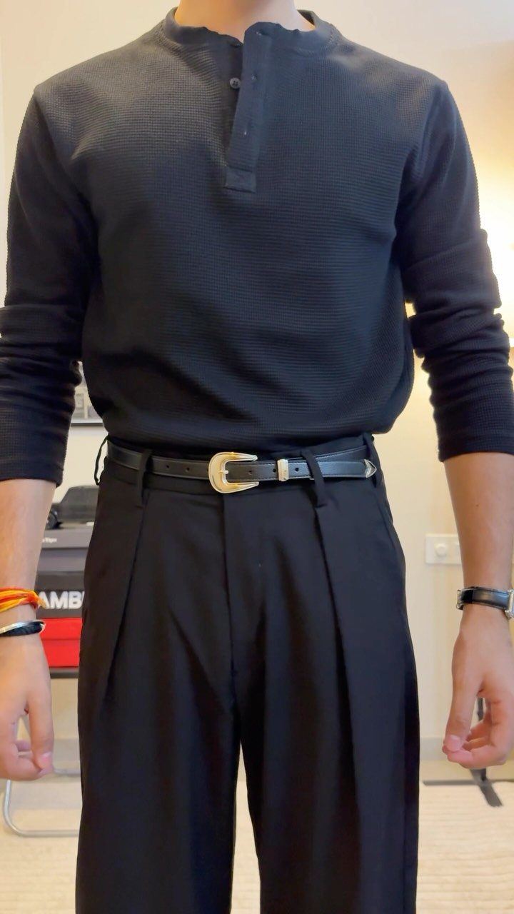 Man wearing a black leather dress belt with a gold buckle and black trousers.