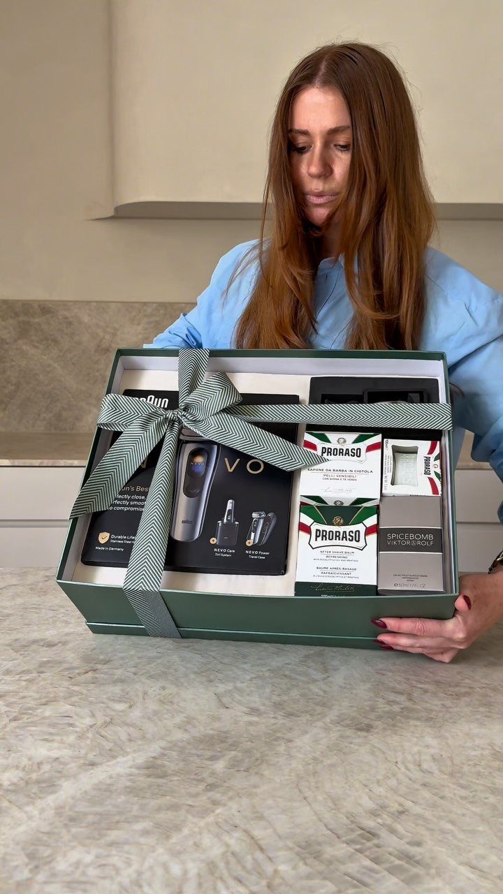 Woman holding a green gift box containing a luxury shaving kit and grooming tools.