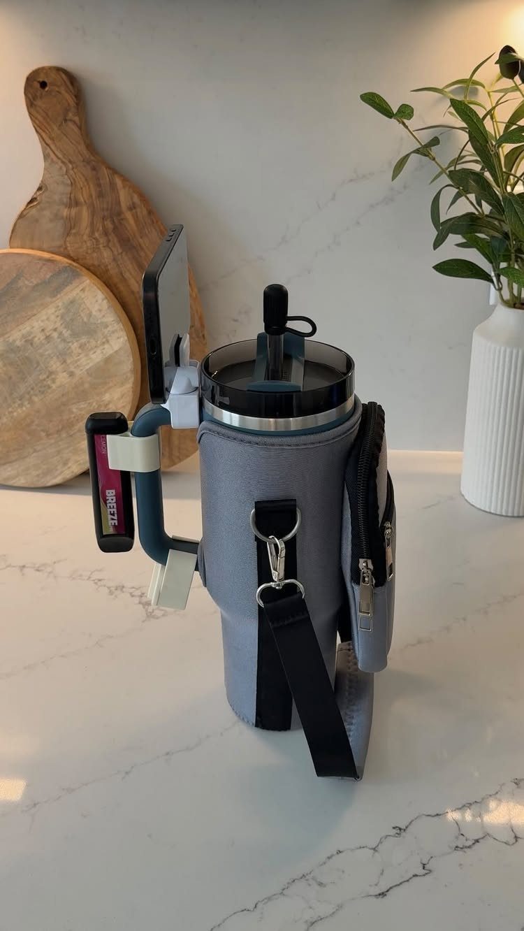 Grey insulated water bottle carrier with phone holder on a white marble counter