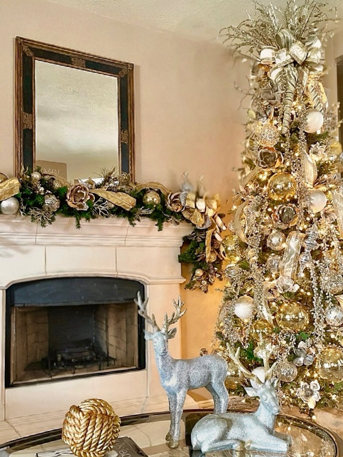 Decorated Christmas tree with gold and silver ornaments next to a white fireplace.