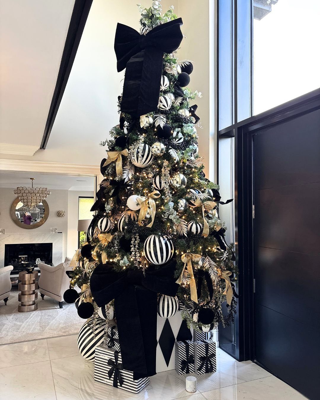Black and white decorated Christmas tree with large bows in a modern room.