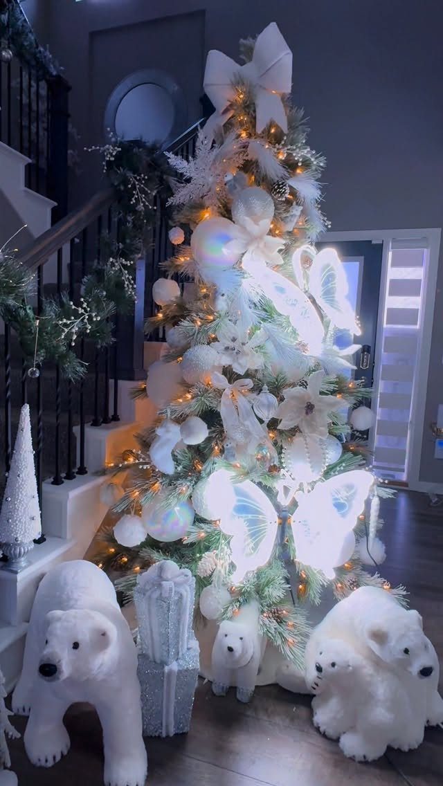 White decorated Christmas tree with white ornaments and plush polar bears at the base.