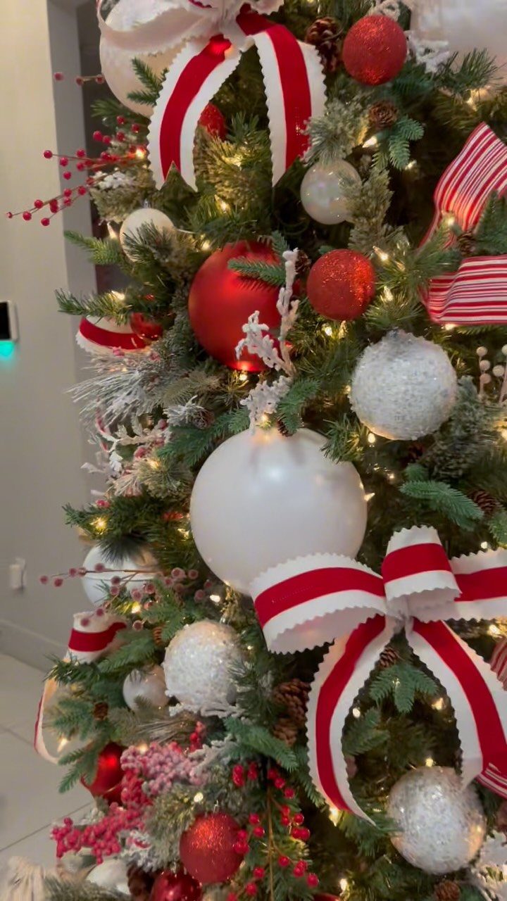 Christmas tree decorated with red and white ornaments and striped ribbons.