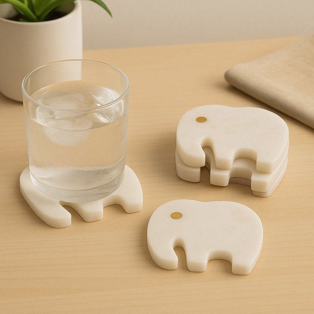 White marble elephant-shaped coasters on a wooden table with a glass of water.
