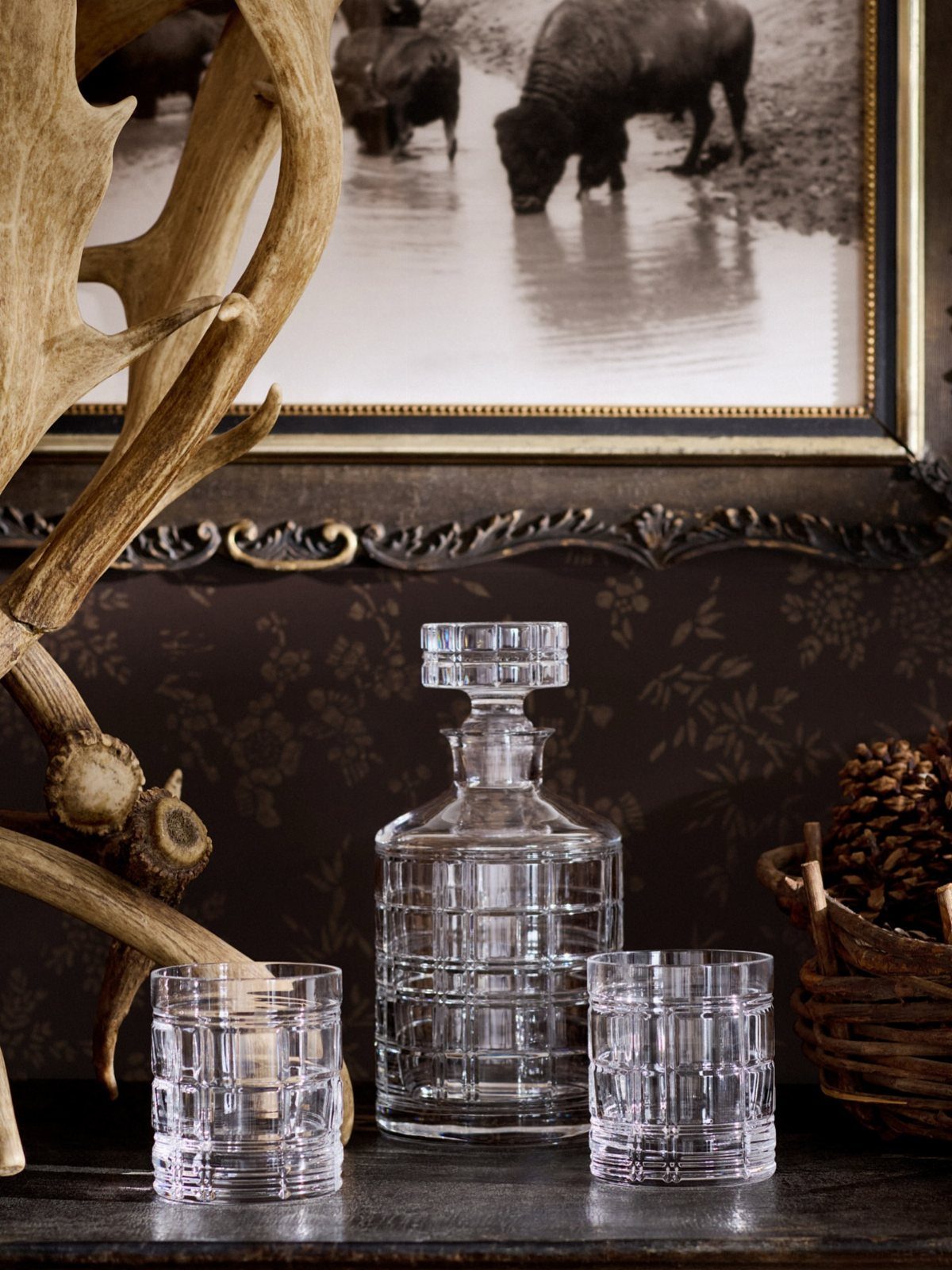Glass decanter and two matching textured glasses on a dark wooden surface.