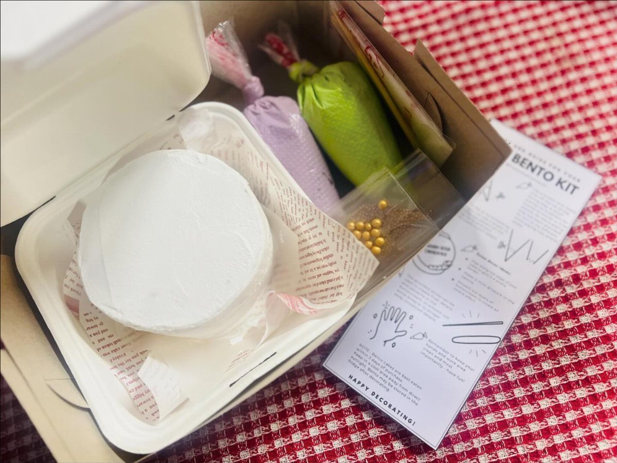 Bento cake decorating kit with frosting bags and instructions on checkered tablecloth