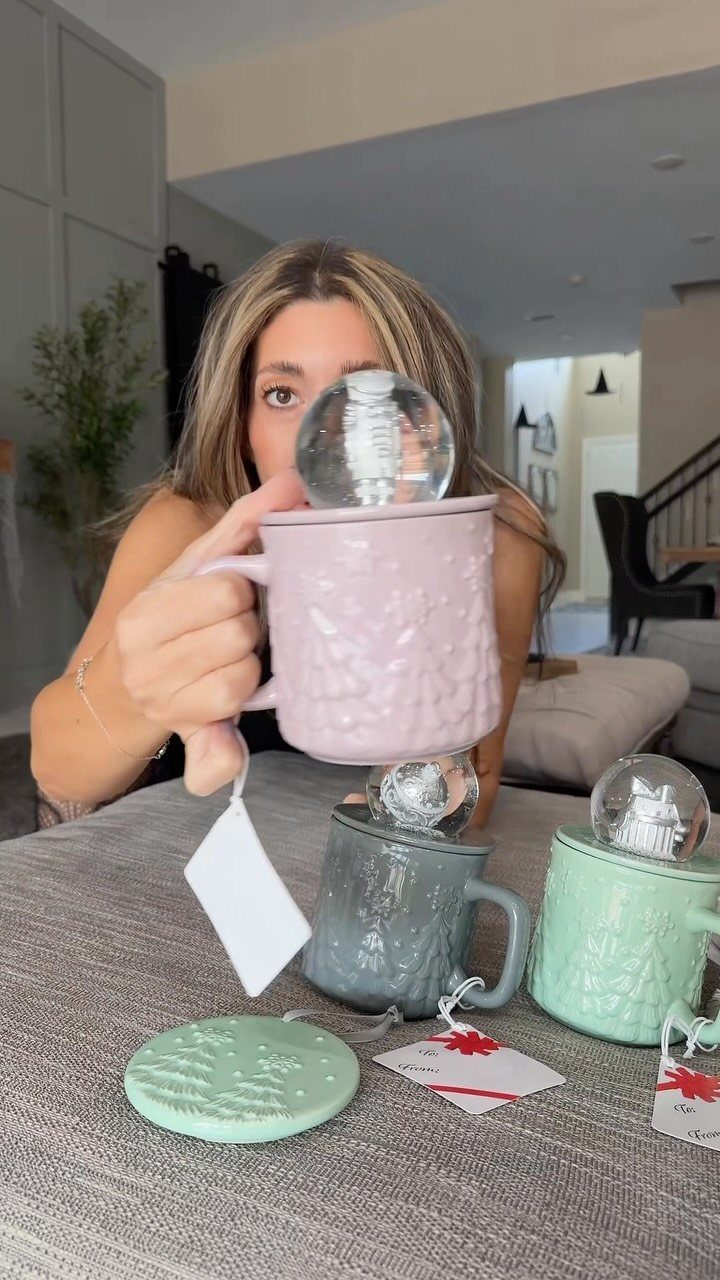 Woman holding a purple textured mug with a snow globe inside as a gift