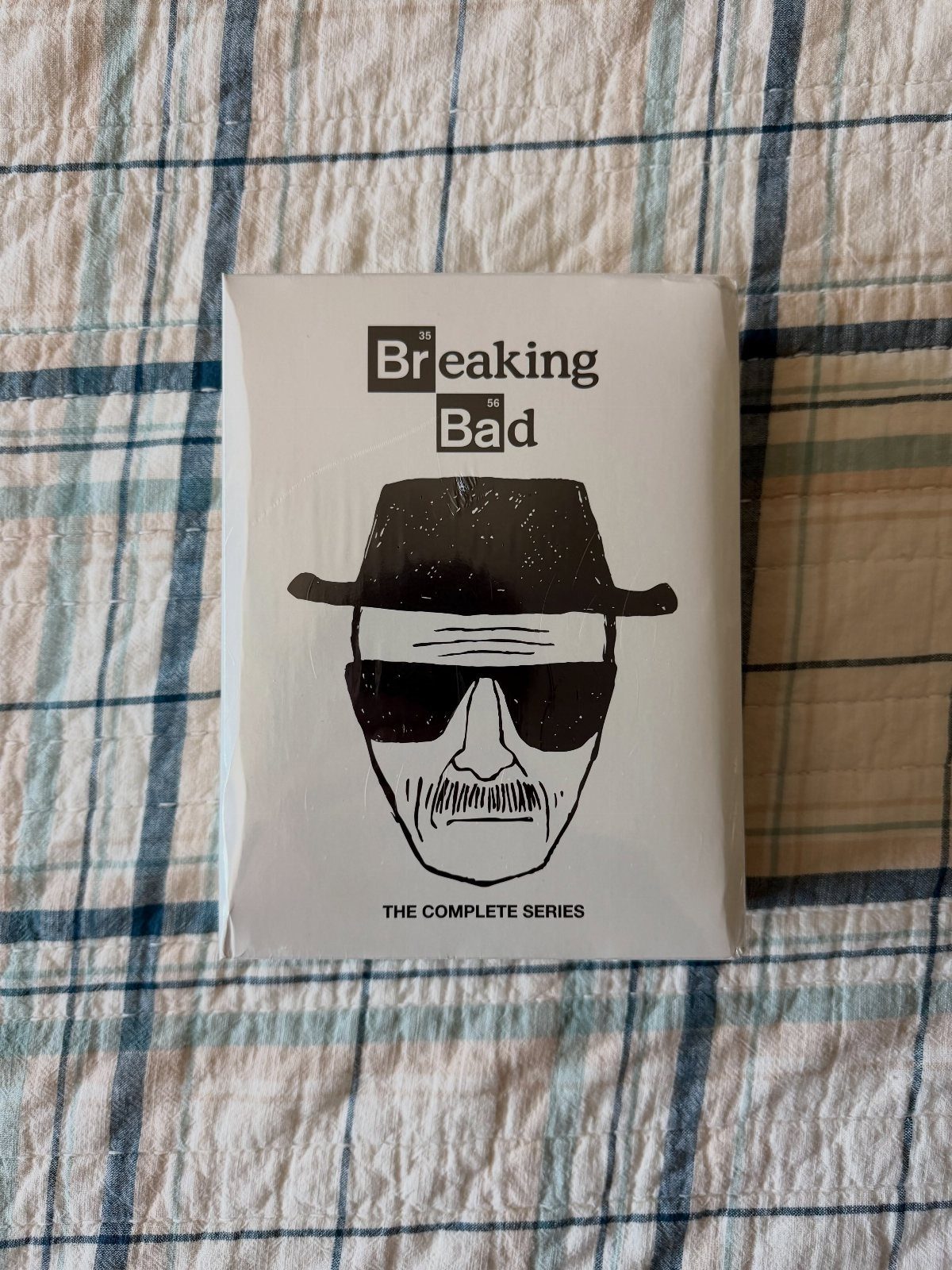 Breaking Bad complete series DVD box set on a blue plaid fabric background