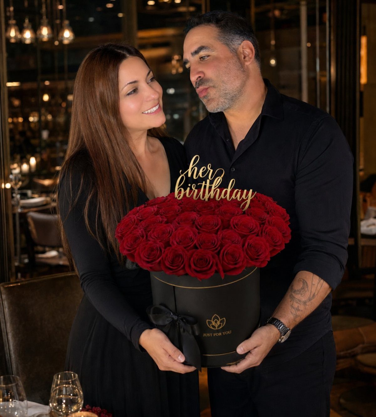 Couple in a restaurant with a large box of red birthday roses