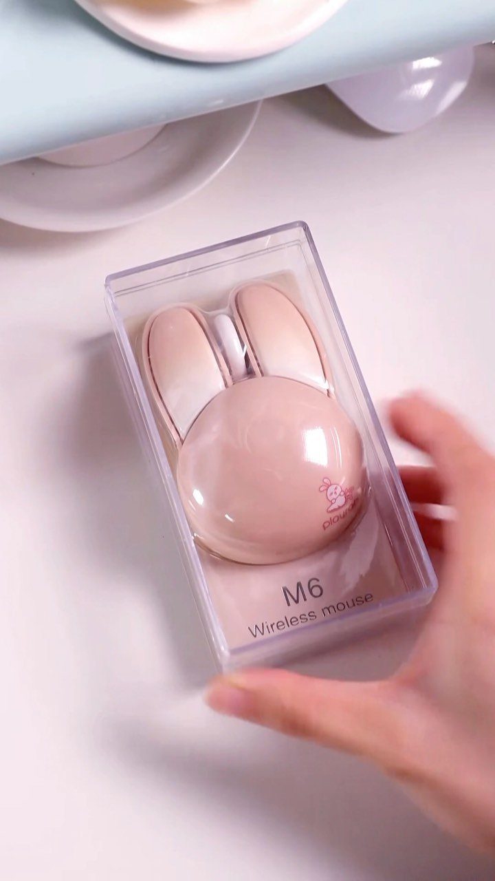 Pink wireless computer mouse with ear shapes inside a clear plastic box.