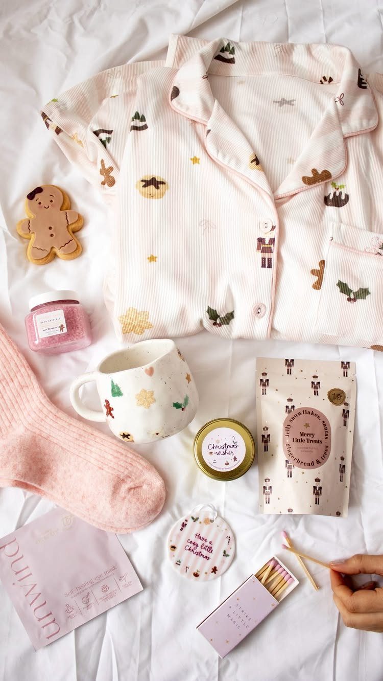 Pink patterned pajamas and cozy winter treats arranged on a white fabric background.
