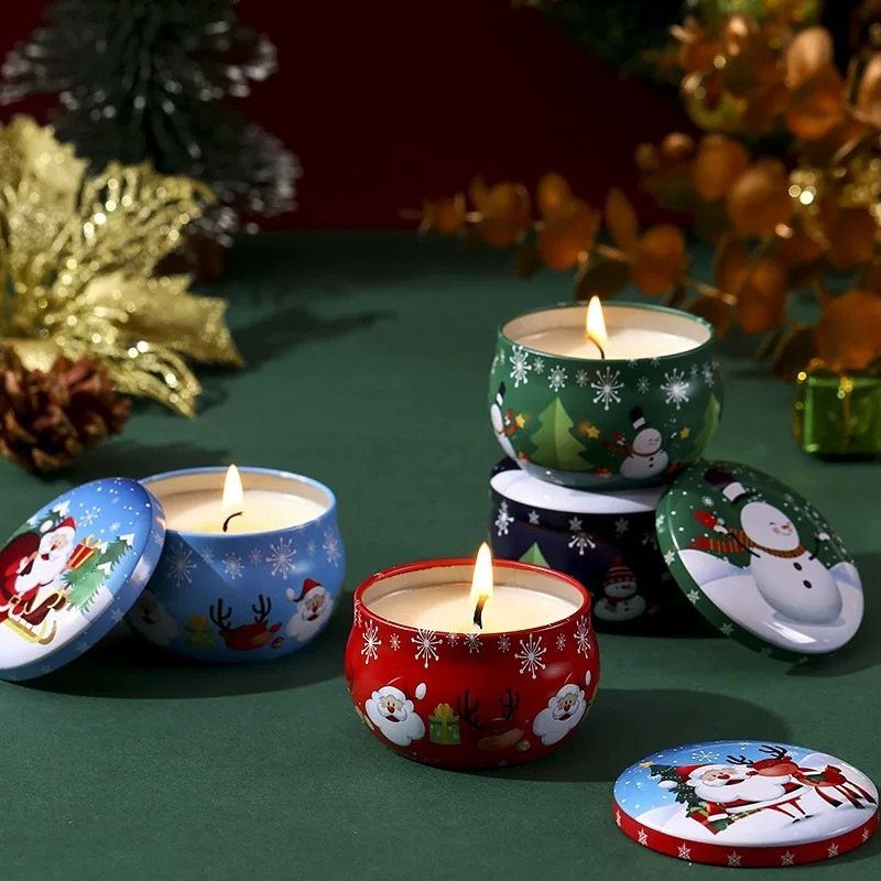 Three lit Christmas themed scented candles in red, blue, and green metal tins.