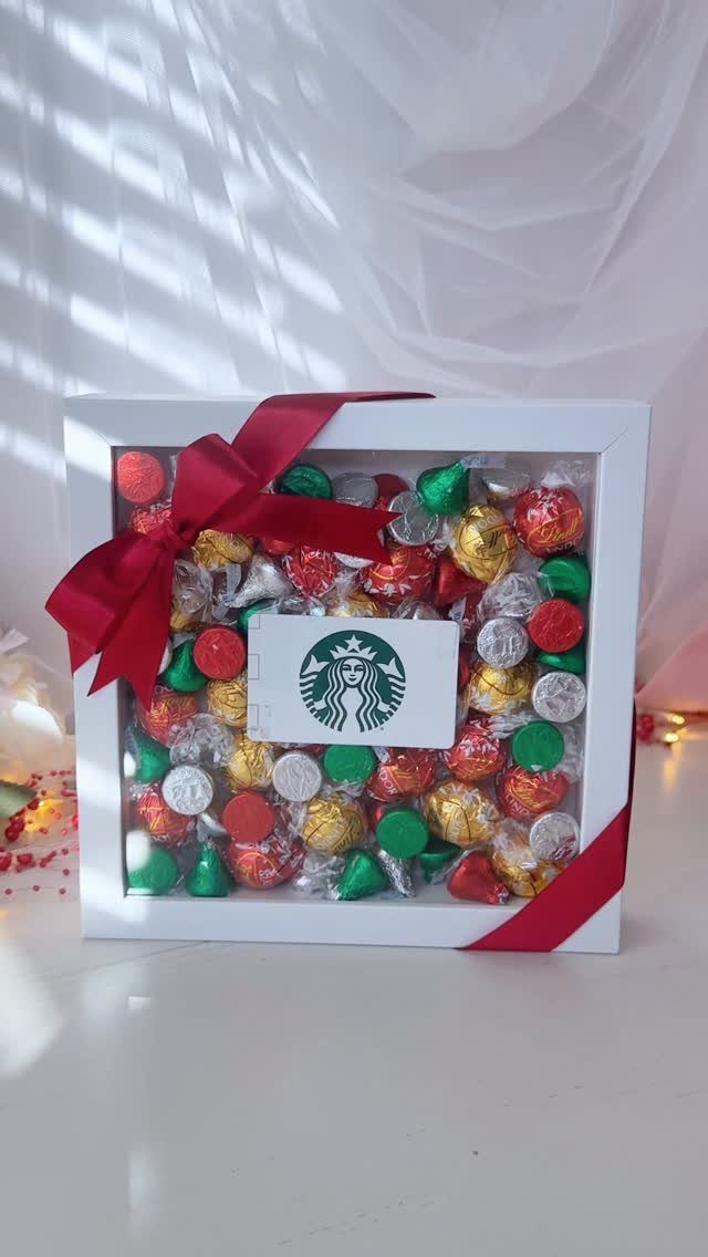 White shadow box filled with colorful chocolates and a Starbucks gift card.