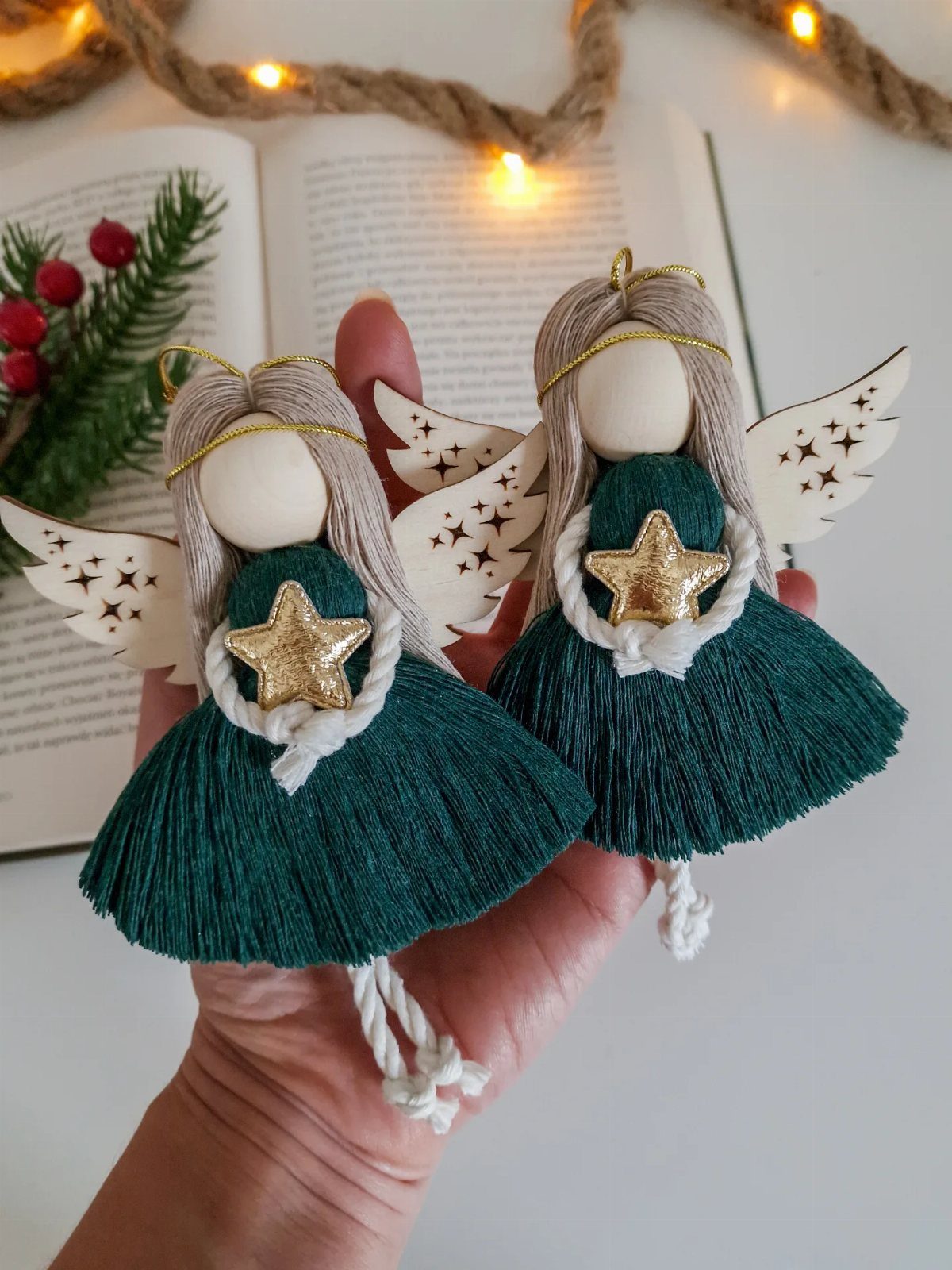 Two handmade angel ornaments with green skirts and gold stars held in a hand.