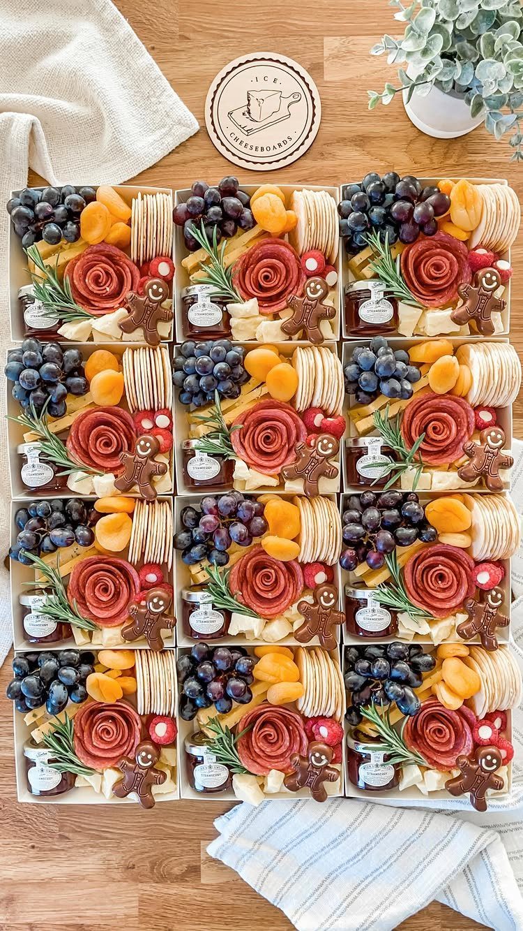 Twelve identical charcuterie gift boxes with gingerbread men on a wooden table