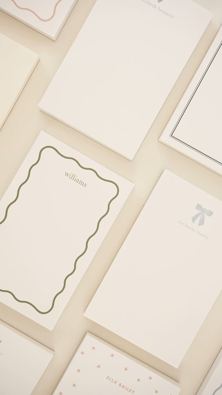 White and cream notebooks with minimalist designs and names printed on the covers.